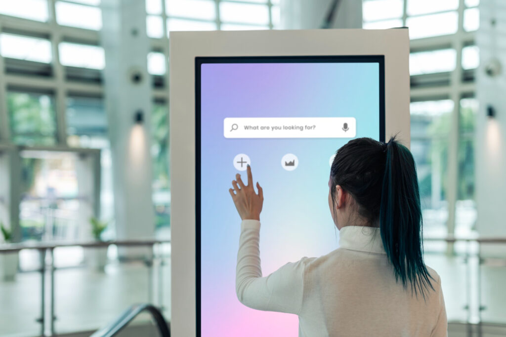 Woman using an interactive digital kiosk in a public space for navigation assistance