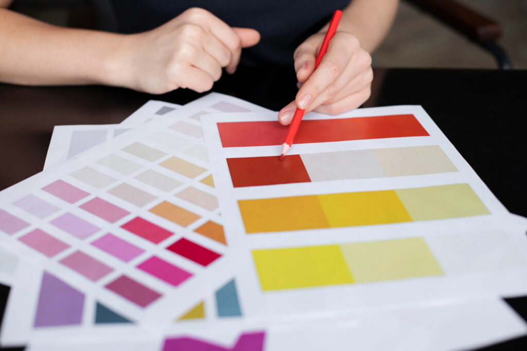 Designer selecting colours from printed colour palette swatches.