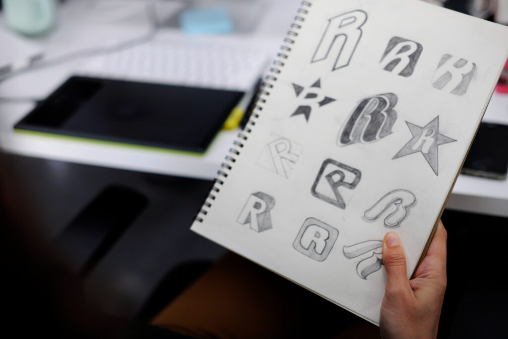 Designer sketchbook showing multiple logo concepts during the brand identity design process